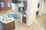 Bright modern dental clinic with wooden floors, dental chair, sink, and cabinetry in treatment area.