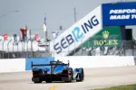 Blue and black racecar on Sebring raceway with Rolex and Sebring signage visible on trackside walls