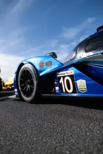 Close-up of blue race car number 10 with WeatherTech and Rolex 24 Daytona logos on asphalt under blue sky.