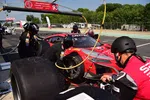 Race car pit crew performing tire change and refueling on red Acura NSX GT3 during motorsport event.