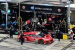 Red Acura race car number 93 in the pit stop with crew under Konica Minolta banner during a GT race.