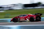 Red Lamborghini race car number 1 with Journey and Palm Beach logos speeding on racetrack with blurred background