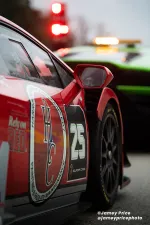 Close-up of red racecar number 25 with sponsor decals near a green racecar at a racing event