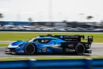 Blue Acura race car number 10 speeds on track during daytime motorsport event with blurred background.
