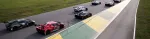 Race cars lined up on a track preparing for a motorsport event under clear daylight conditions.