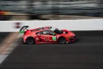 Red racecar number 93 speeding on a racetrack with blurred background and large rear wing