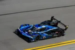 Blue and black Acura prototype race car number 10 speeding on racetrack near yellow lines.