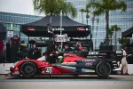 Red and black Acura race car number 40 in pit lane with crew and black Acura DEX Imaging tents in background.