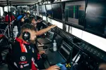 Race team engineers monitoring live data and race performance on multiple screens in a motorsport control room.