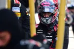 Racecar driver in black and red Acura racing suit and helmet in the pit lane focused before the race.