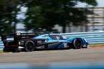 Blue and black race car number 10 speeding on track with blurred background and sponsor logos