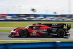 Red and black Acura racing car number 40 speeding on a racetrack with blurred background motion effect.
