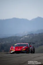 Red Lamborghini racing car on track with mountainous background under clear sky during race event