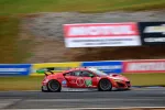 Red Acura NSX GT3 race car number 93 speeding on track with blurred background and Motul advertising banners.