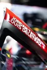 Close-up of a race car halo with driver names Jordan Taylor and Louis Deletraz in white on red background.