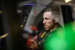 Focused race car driver seated inside car cockpit preparing for a race with intense concentration.