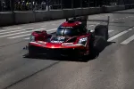 Red and black Acura DPi race car number 40 driving on a city street track with spectators behind barricades.
