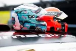 Two racing helmets with distinct designs, one blue with graffiti and one red, placed side by side on a vehicle.