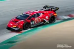 Red race car with number 25 speeds on race track corner with sponsor logos and aerodynamic wing in motion blur.
