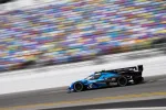 Blue and black racing car speeding on a racetrack with blurred colorful grandstands in the background
