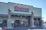 Costco Wholesale store entrance with visible signage and customers walking in and out during daytime.