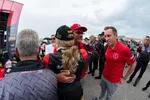 Race car driver celebrating with team members after winning first place at a motorsport event.