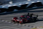 Red and black Acura DPi race car number 40 speeding on a racetrack with blurred background.