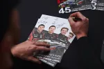 Person signing GT3 EVO2 Lamborghini Huracan racing team posters with drivers' portraits and car image.