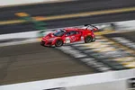 Red racing car number 93 speeding on a race track with blurred background and sponsor logos.