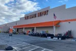 The Home Depot storefront with an outdoor display of grills, chairs, and gardening supplies under a partly cloudy sky.