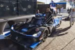 Black and blue Acura racing car with number 10 and Konica Minolta branding at race track pit area.