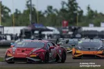 Red and black Lamborghini race car number 25 leading another Lamborghini on a racetrack during a competitive race.