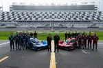 Race teams pose with red and blue prototype race cars on track at the World Center of Racing stadium.