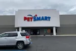 Front view of a PetSmart store with a gray SUV parked outside on a cloudy day.