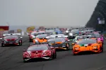 Multiple Lamborghini Huracán race cars competing on a track during a motorsport event in cloudy weather.