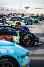 Close-up of multiple colorful race cars lined up on a track ready for a motorsport event.