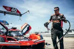 Race crew member refueling red Acura DPi race car number 40 during pit stop under clear sky.