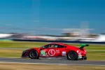 Red Acura NSX GT3 race car number 93 speeding on racetrack with sponsor logos and green rear wing in clear daylight.