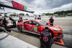 Red Acura NSX GT3 race car number 93 in pit stop with crew during motorsport event under cloudy sky