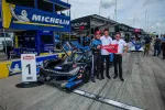 Race car and team celebrating first place at pit lane with Michelin banners and Acura branding visible