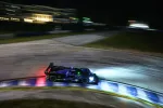 Nighttime racing car speeding on curved track with bright headlights and blurred motion effect