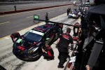 Black and red race car number 45 in pit stop with crew working during a motorsport event.