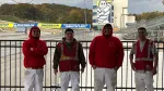 Four workers in red hoodies and safety vests stand in front of a race track with Michelin banners and the Michelin Man logo.