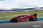 Red Lamborghini race car number 25 speeding on racetrack with blurred background and sponsor logos.