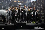 Winning race car drivers celebrating on Super Trofeo podium holding trophies in racing suits and caps.