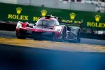Red Acura race car speeding on track during a race with Rolex advertising boards in the background