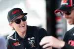 Two racing drivers wearing DEX Imaging caps and shirts smiling and interacting in a casual setting.