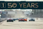 Electric race cars speeding on track under 50 Years banner at a professional motorsport event