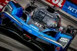 Close-up of a blue Acura Konica Minolta IMSA race car on the track with LED headlights and sponsor decals.