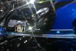 Race car driver wearing Bell helmet inside a racing car cockpit with illuminated steering wheel controls.